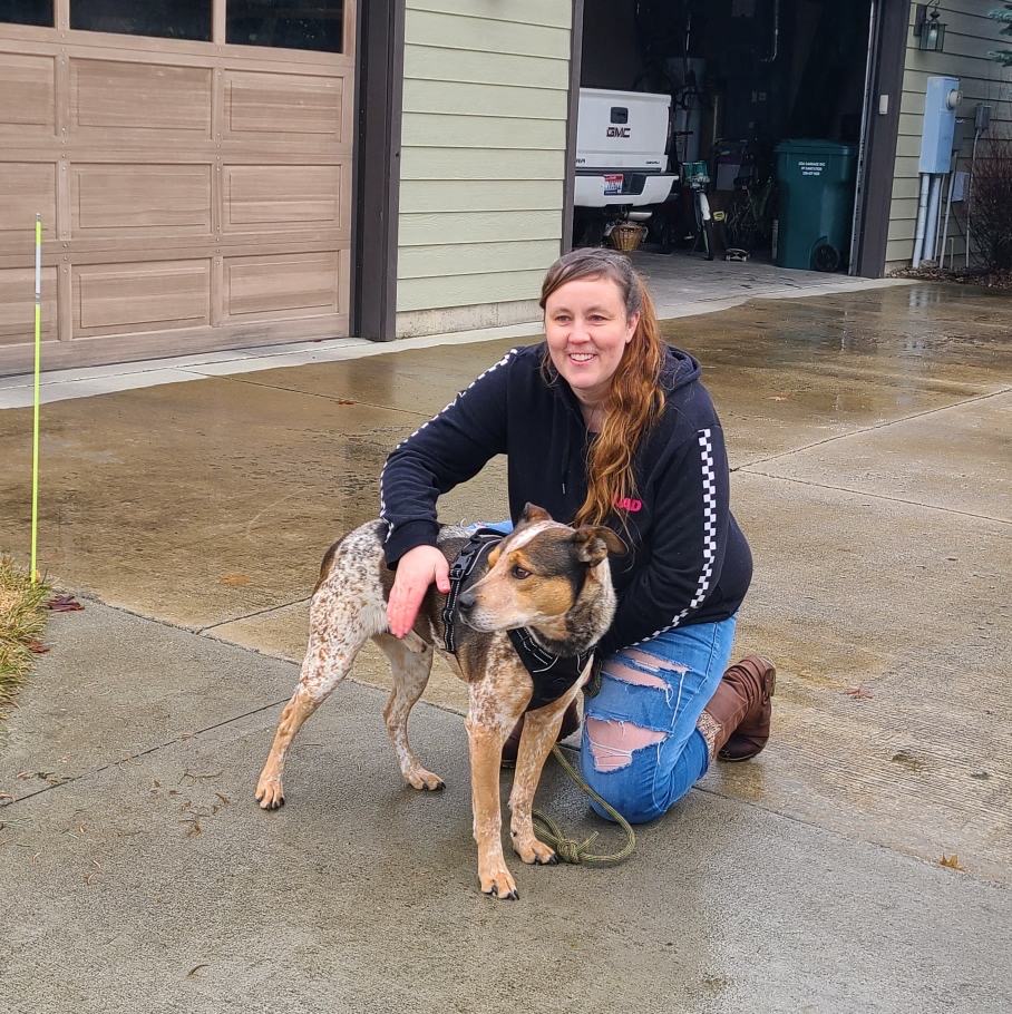 Carrie Adams, founder of Red Waggin' Rescue, kneeling beside a rescue dog