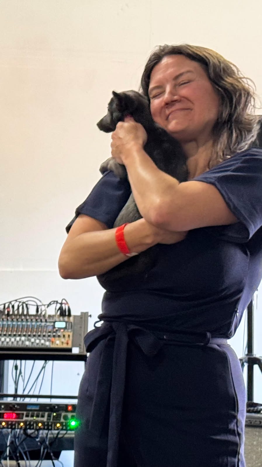 Jen cuddling a small black rescue dog at a rescue event