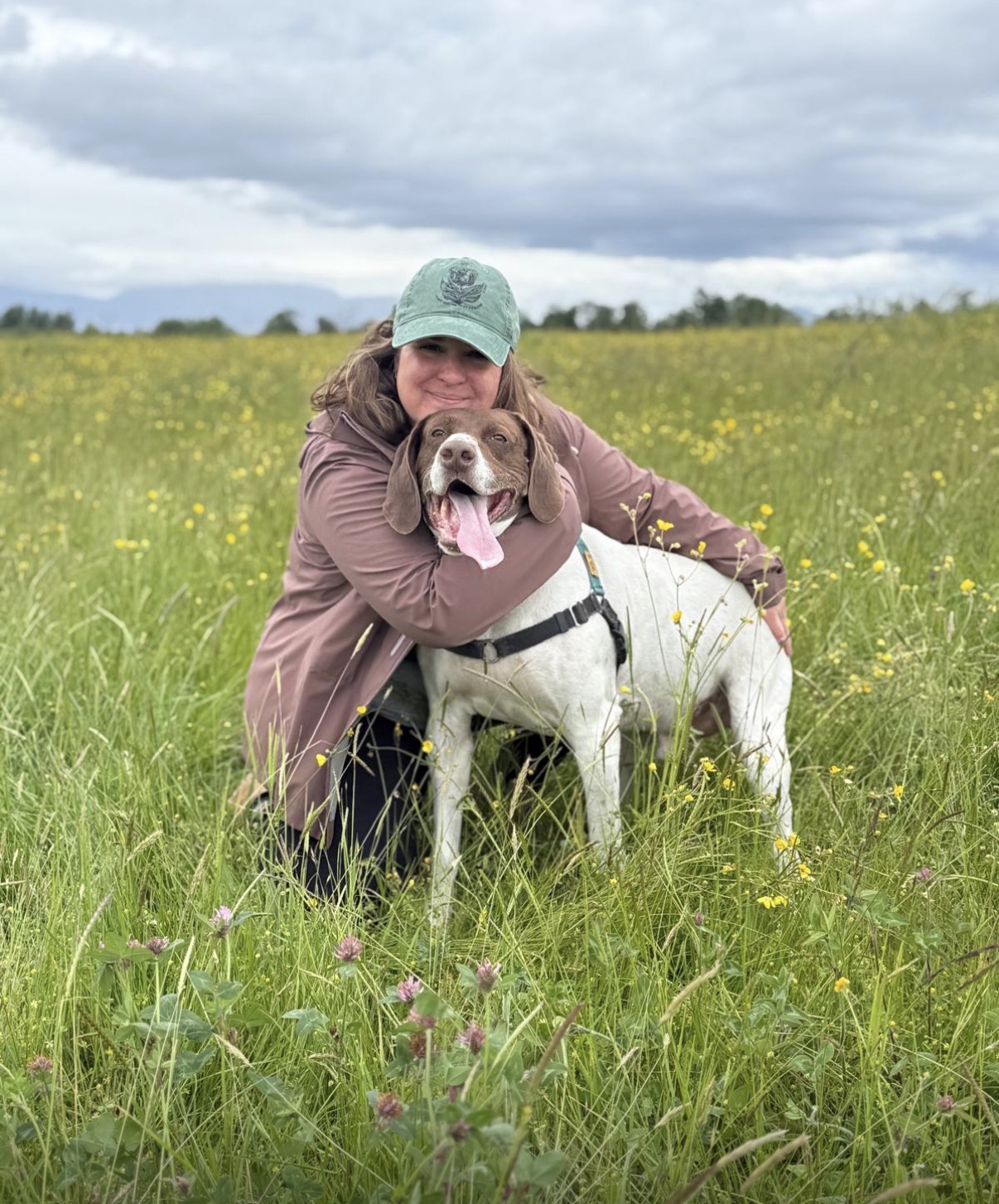 Domenica hugging a rescue dog in a wildflower field