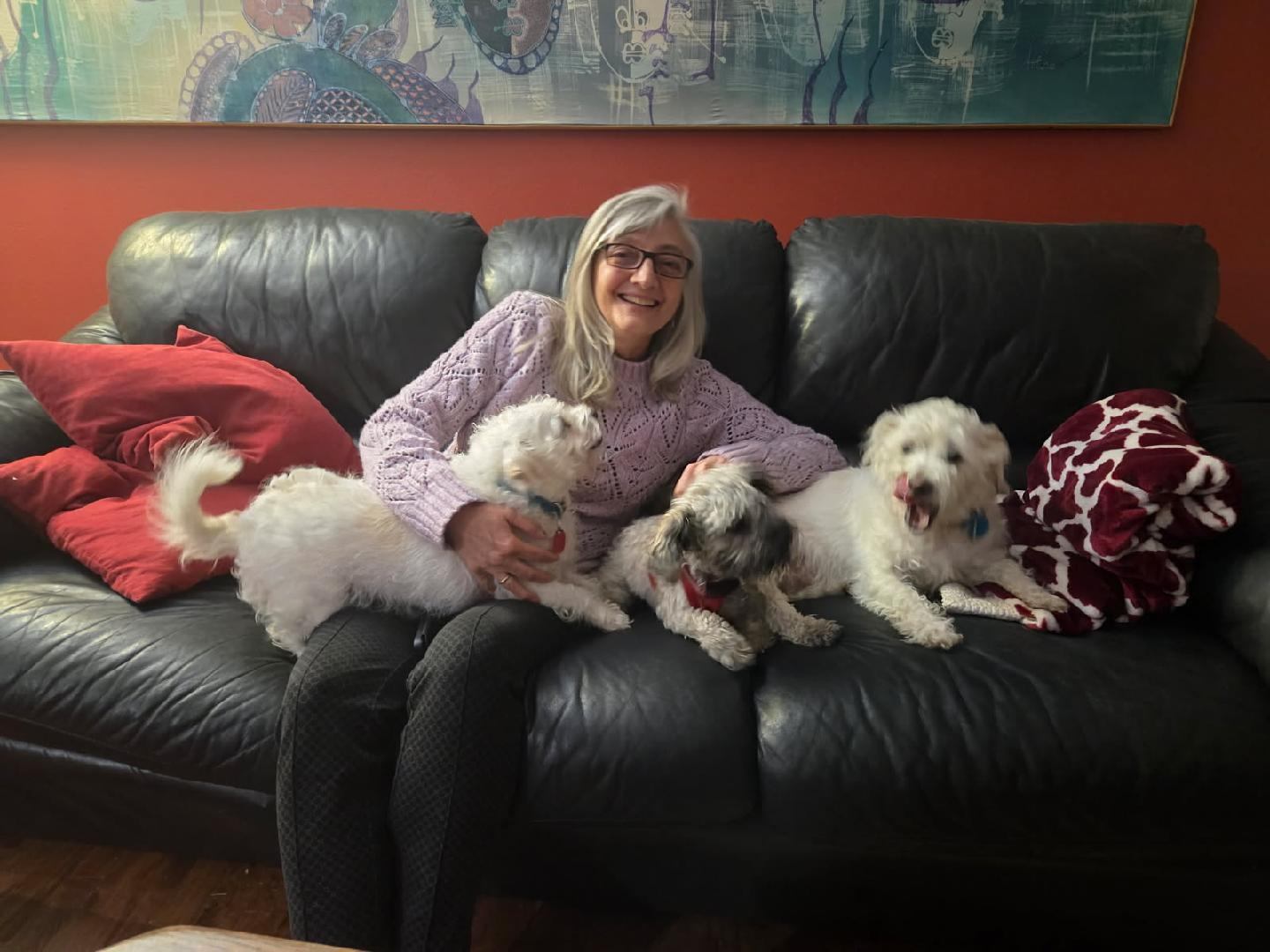 Elena relaxing on the couch with three small rescue dogs