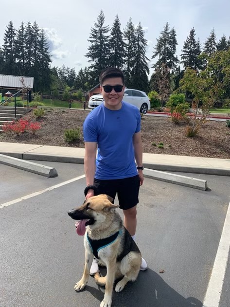 Adopter standing outside with his German Shepherd mix on a sunny Washington day