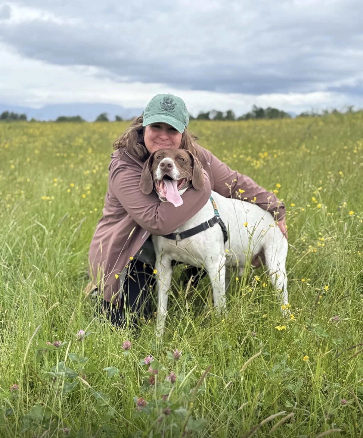 Domenica hugging a rescue dog in a wildflower field